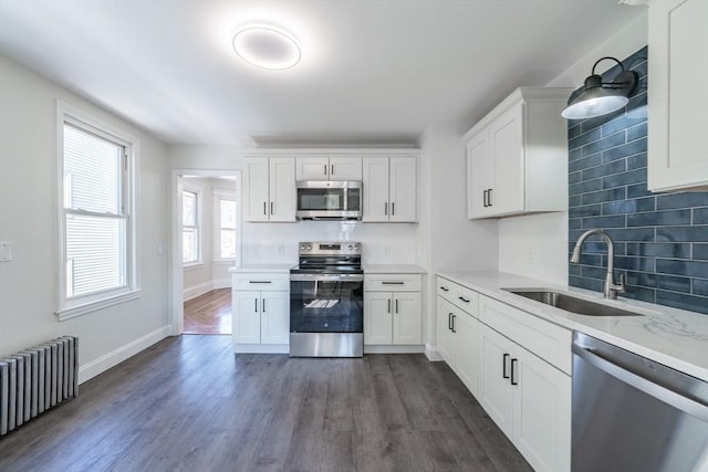 kitchen with white cabinetry, appliances with stainless steel finishes, and radiator heating unit