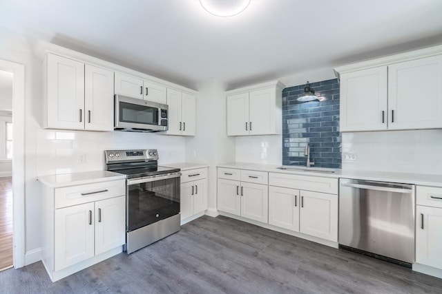 kitchen with sink, white cabinetry, tasteful backsplash, appliances with stainless steel finishes, and light hardwood / wood-style floors