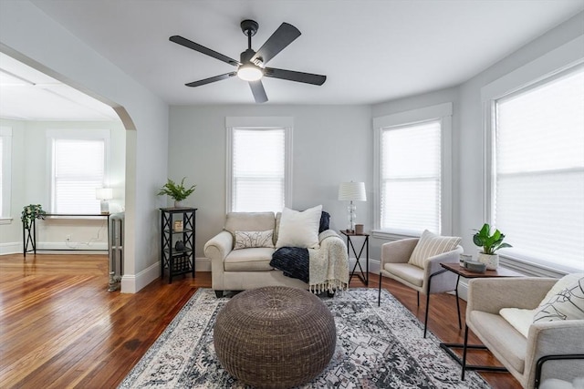 living room with a healthy amount of sunlight, dark wood-type flooring, and ceiling fan