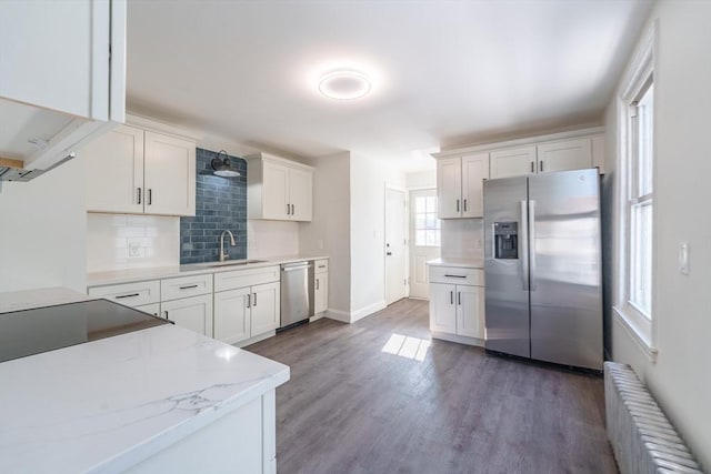 kitchen featuring stainless steel appliances, white cabinetry, tasteful backsplash, and radiator heating unit