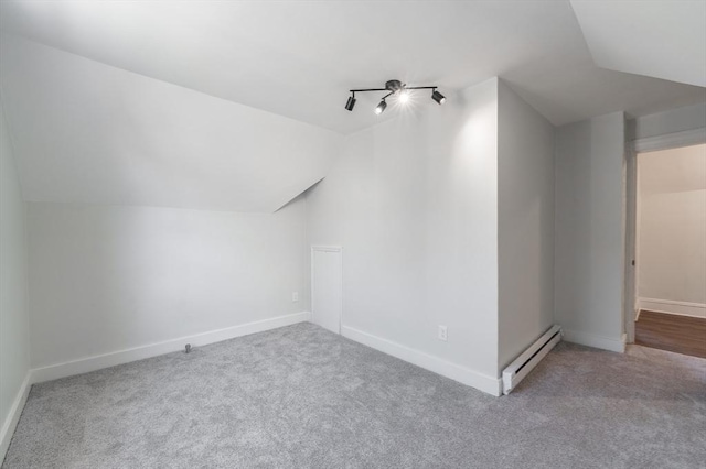 additional living space with a baseboard radiator, lofted ceiling, and light carpet