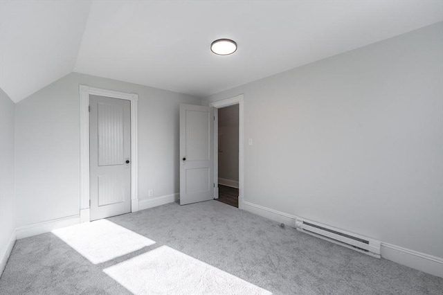 unfurnished bedroom featuring a baseboard heating unit, vaulted ceiling, and carpet flooring