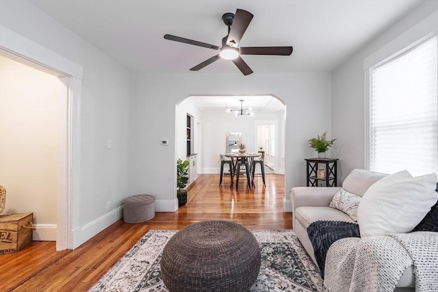 living room with ceiling fan with notable chandelier and light wood-type flooring