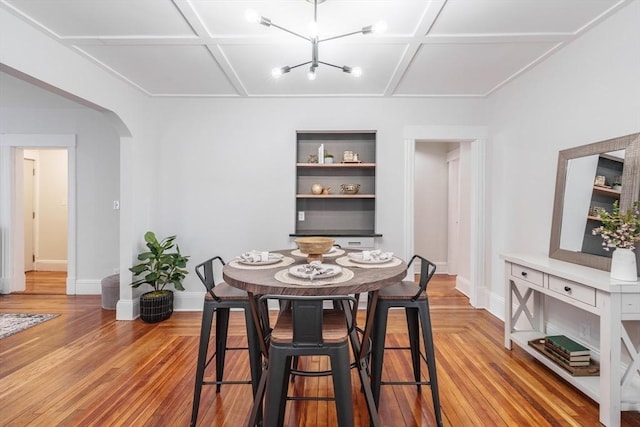 dining area with coffered ceiling and light hardwood / wood-style floors