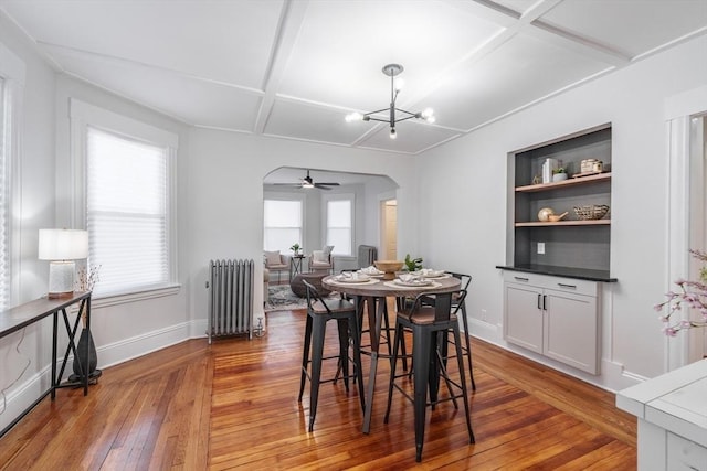 dining space with coffered ceiling, a chandelier, plenty of natural light, radiator, and hardwood / wood-style floors