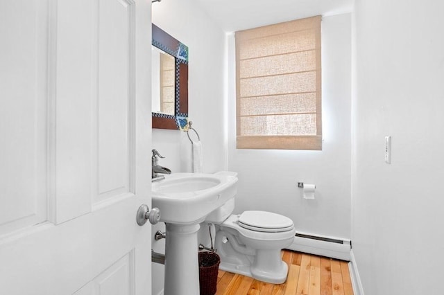 bathroom with a baseboard radiator, toilet, and hardwood / wood-style floors