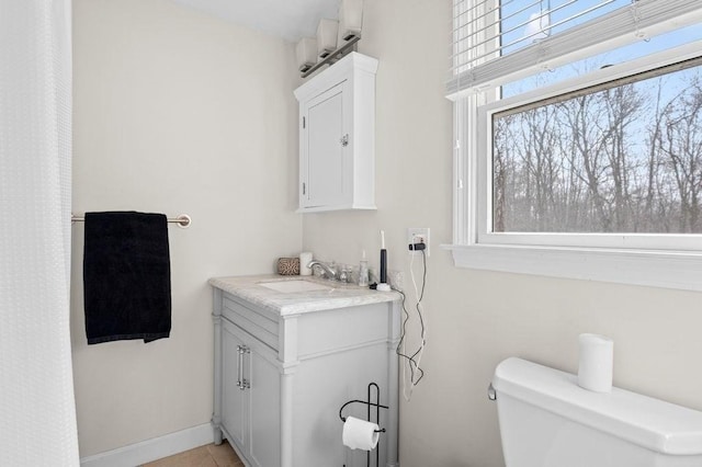 bathroom featuring vanity, a wealth of natural light, tile patterned floors, and toilet