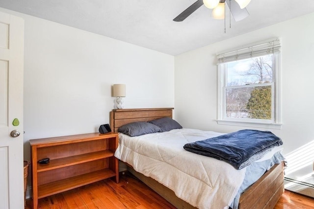 bedroom featuring baseboard heating, ceiling fan, and hardwood / wood-style floors