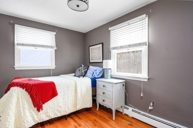 bedroom featuring light hardwood / wood-style flooring and a baseboard heating unit