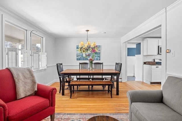 dining space with ornamental molding, a chandelier, and light wood-type flooring