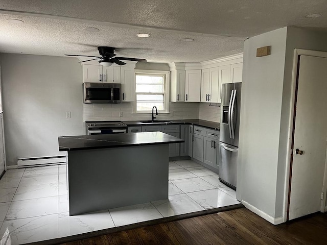 52-54 Campechi St, Springfield, MA 01104 - kitchen featuring stainless steel appliances, a baseboard radiator, dark countertops, light marble finish floors, and a textured ceiling