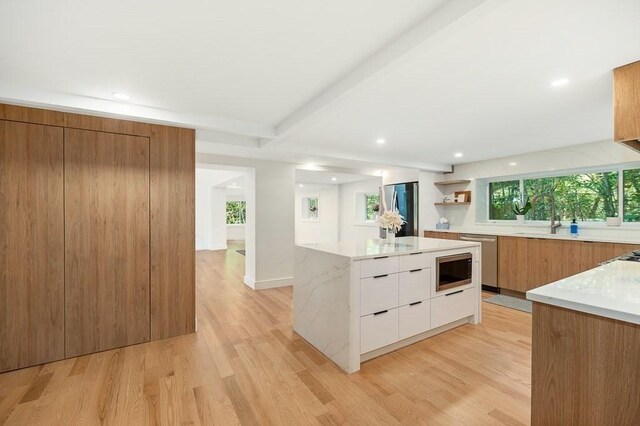 kitchen with light hardwood / wood-style floors, beamed ceiling, white cabinets, a kitchen island, and stainless steel appliances