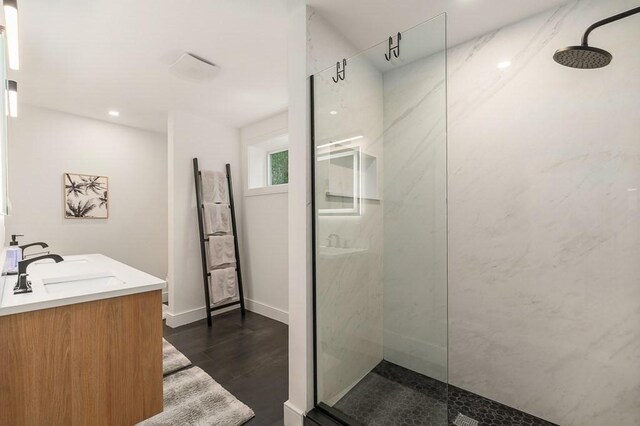 bathroom featuring a tile shower, vanity, and hardwood / wood-style floors