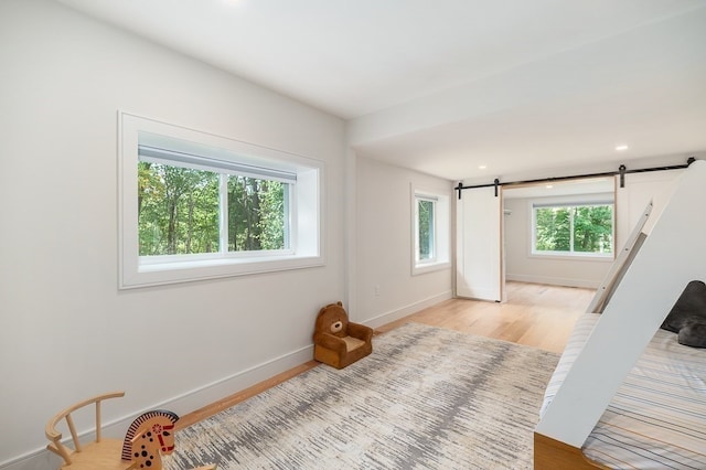 bedroom featuring a barn door and light wood-type flooring