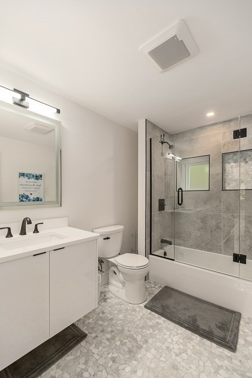 full bathroom featuring enclosed tub / shower combo, vanity, and toilet