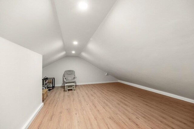 bonus room with light wood-type flooring and vaulted ceiling