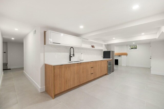 kitchen with decorative backsplash, white cabinetry, light tile patterned floors, and sink