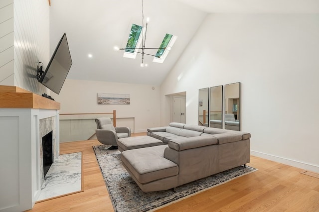 living room with light hardwood / wood-style floors, a high end fireplace, a skylight, and high vaulted ceiling