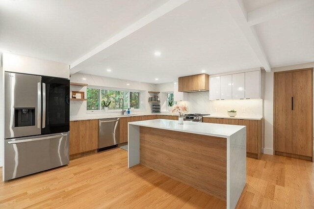 kitchen with beamed ceiling, light hardwood / wood-style flooring, white cabinetry, stainless steel appliances, and decorative backsplash