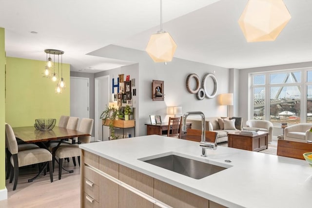 kitchen featuring decorative light fixtures, open floor plan, light countertops, and a sink