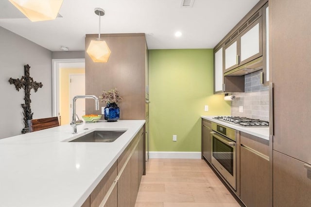 kitchen with tasteful backsplash, baseboards, light countertops, appliances with stainless steel finishes, and a sink