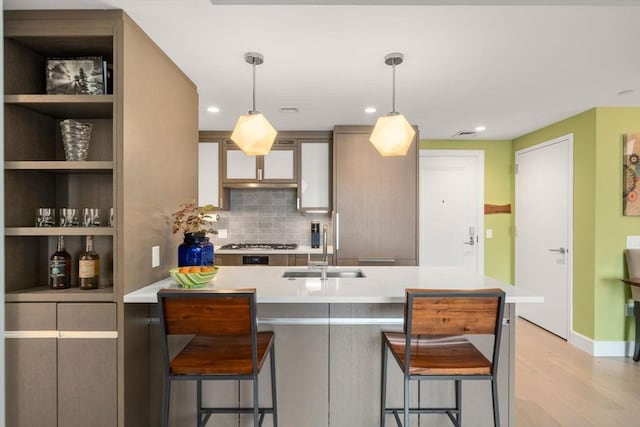 kitchen with light countertops, a kitchen breakfast bar, light wood-style floors, and a sink