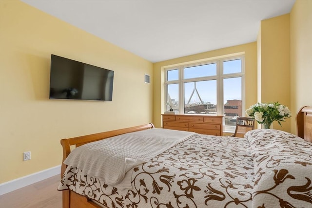 bedroom with light wood-style flooring, visible vents, and baseboards