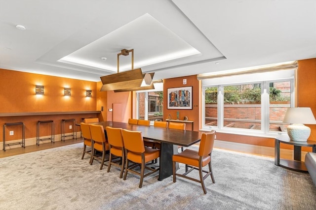 dining area featuring baseboards, a tray ceiling, and wood finished floors