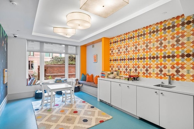 playroom with a sink, baseboards, and a raised ceiling