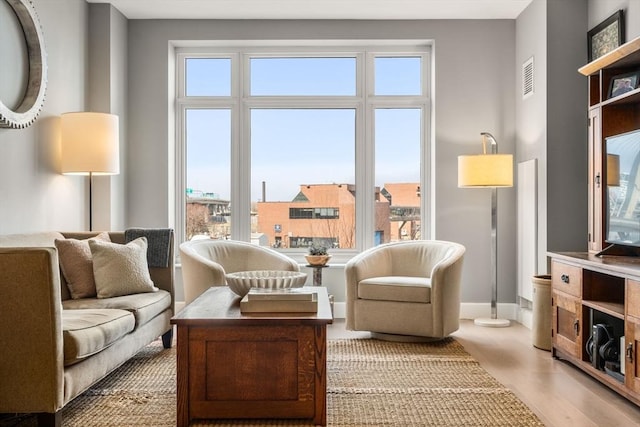 living area with visible vents, baseboards, and light wood-style floors