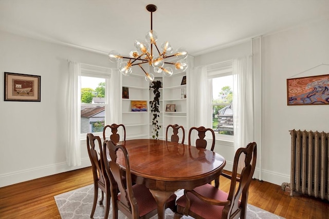 dining area featuring radiator heating unit, a chandelier, wood finished floors, and baseboards