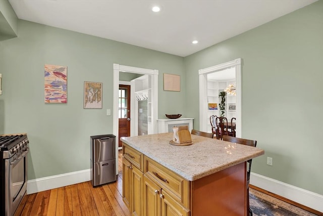kitchen featuring stainless steel range with gas cooktop, light wood-style flooring, baseboards, light stone countertops, and recessed lighting