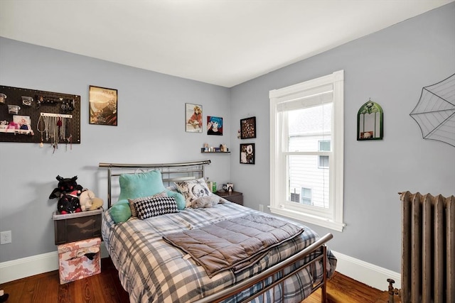 bedroom with radiator heating unit, baseboards, and wood finished floors