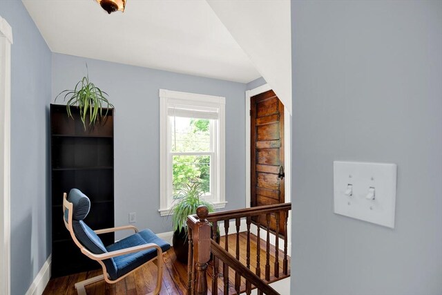 living area with an upstairs landing, wood finished floors, and baseboards