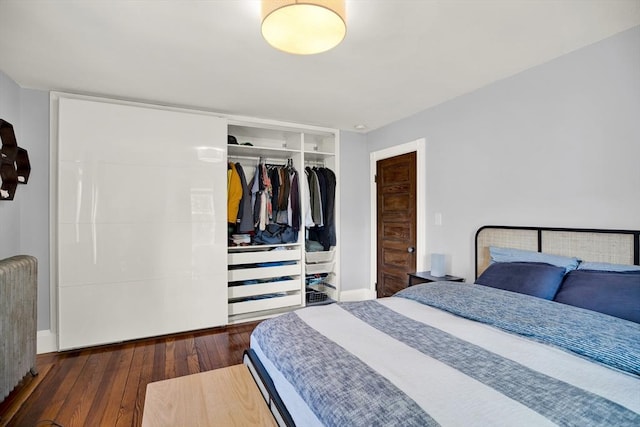 bedroom featuring radiator, a closet, wood-type flooring, and baseboards