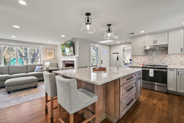 kitchen with dark hardwood / wood-style flooring, a kitchen island, stainless steel range oven, and white cabinetry