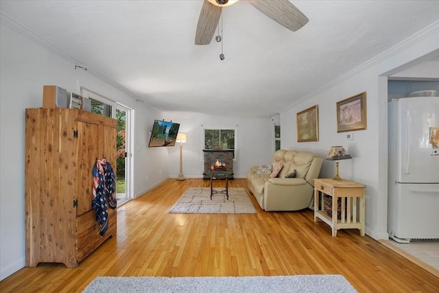42 Beechwood Dr, Mashpee, MA 02649 - living room featuring light wood-style flooring, crown molding, a ceiling fan, and a stone fireplace