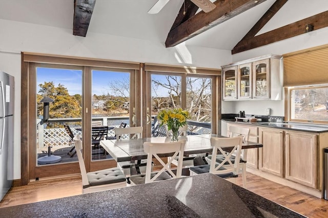 dining room featuring vaulted ceiling with beams, a ceiling fan, and light wood-style floors