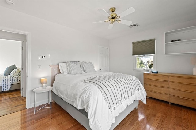 bedroom with visible vents, ceiling fan, baseboards, and wood finished floors