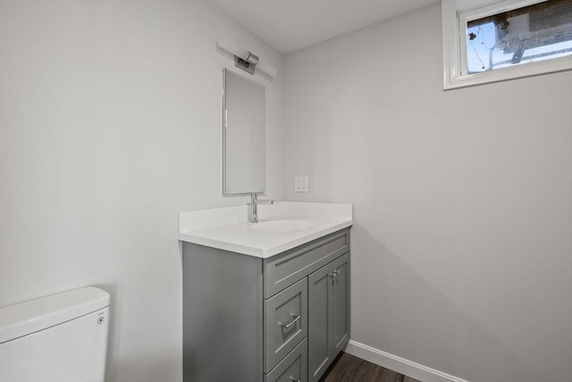 bathroom featuring toilet, vanity, baseboards, and wood finished floors