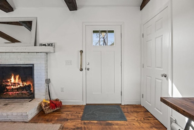 entrance foyer featuring a fireplace, baseboards, beam ceiling, and wood finished floors