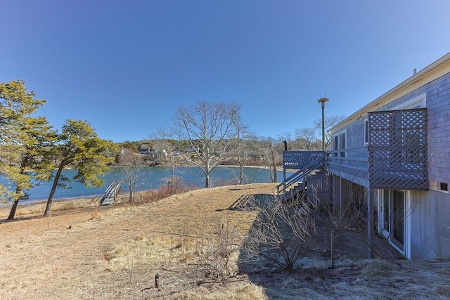 view of yard with stairs and a deck with water view