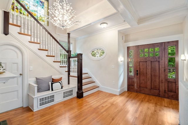 foyer entrance with beamed ceiling, crown molding, and light wood-type flooring