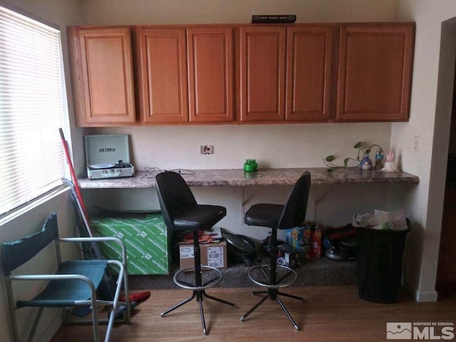office with plenty of natural light, built in desk, and light wood-type flooring