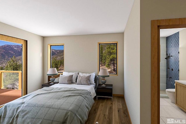 bedroom featuring connected bathroom and light hardwood / wood-style flooring