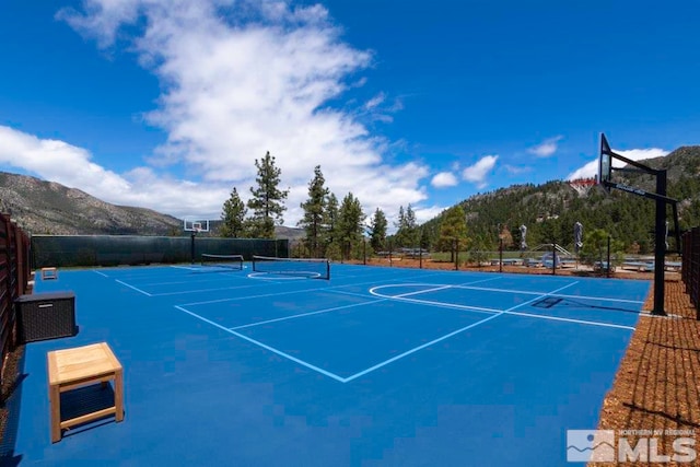 view of sport court with a mountain view and basketball hoop