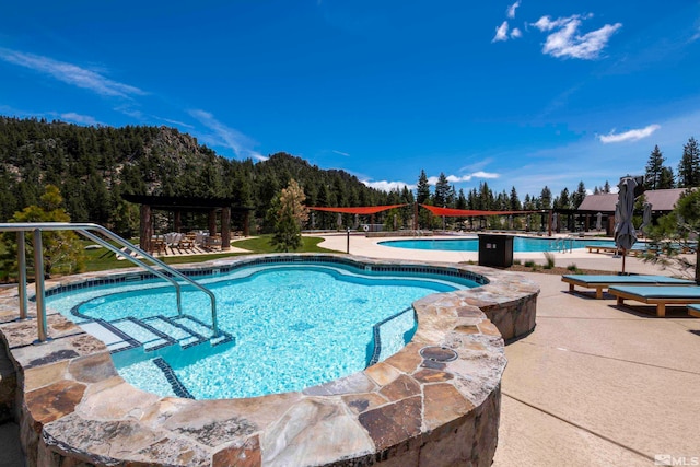 view of swimming pool featuring a patio and a hot tub