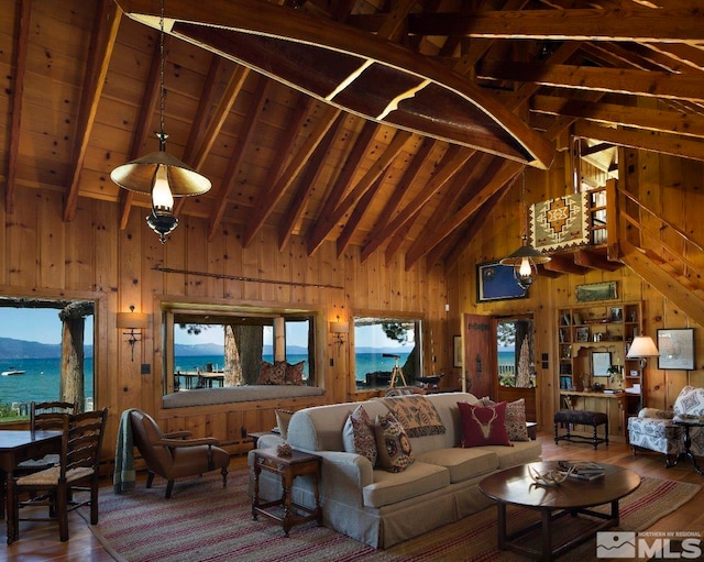 living room with a water and mountain view, wood walls, dark wood-type flooring, and beam ceiling