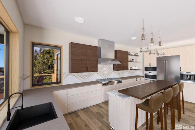 kitchen with pendant lighting, appliances with stainless steel finishes, wall chimney exhaust hood, backsplash, and dark hardwood / wood-style floors