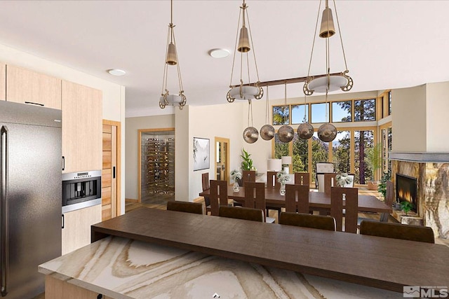 kitchen with pendant lighting, light brown cabinetry, stainless steel oven, and black refrigerator